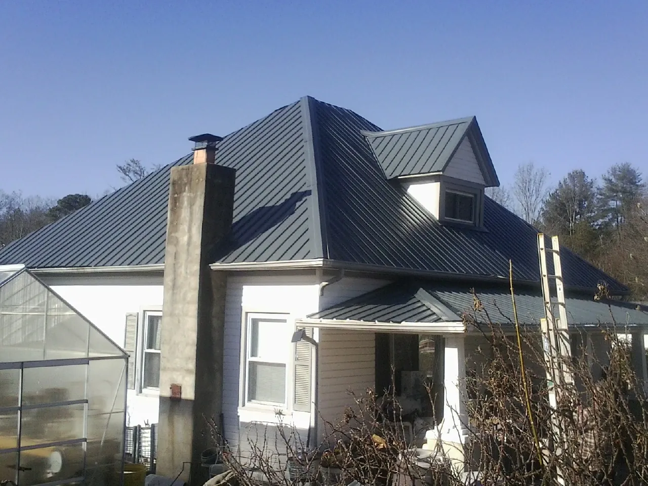 Dark blue standing seam metal roof on a white farmhouse with dormer — Slate & Tile Roof Repair by Roofing Brothers in Cuba