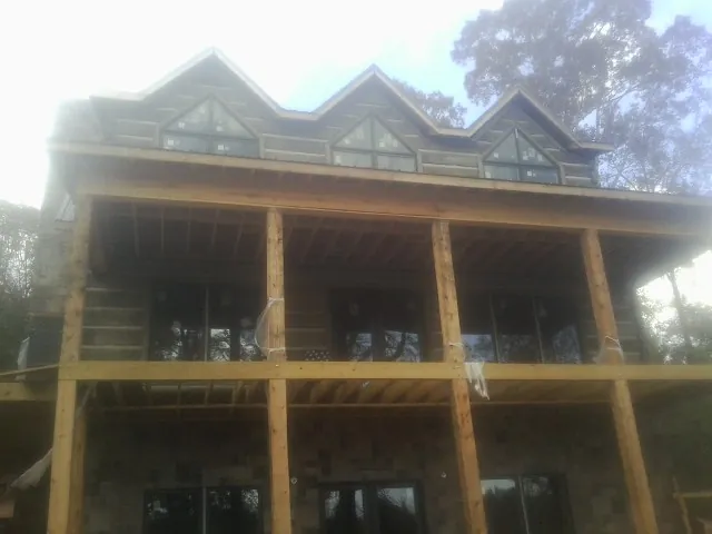 Dormers and porch framing on a large log home under construction — Roof Coating work by our crew in Cuba